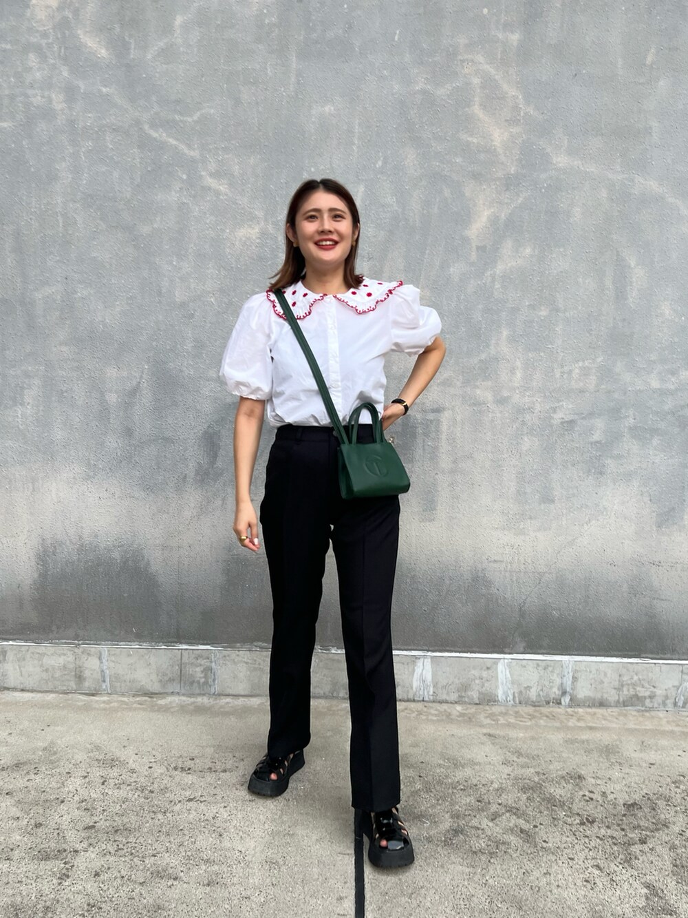 ホワイト系のシャツ/ブラウス、グリーン系のバッグ、ブラック系のパンツを着用したレディースの秋コーディネートの2枚目の写真