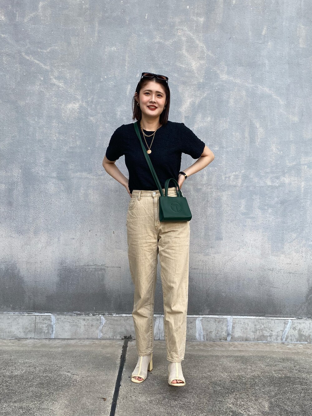 ブラック系のTシャツ/カットソー、グリーン系のバッグ、ベージュ系のデニムパンツを着用したレディースの春コーディネートの2枚目の写真