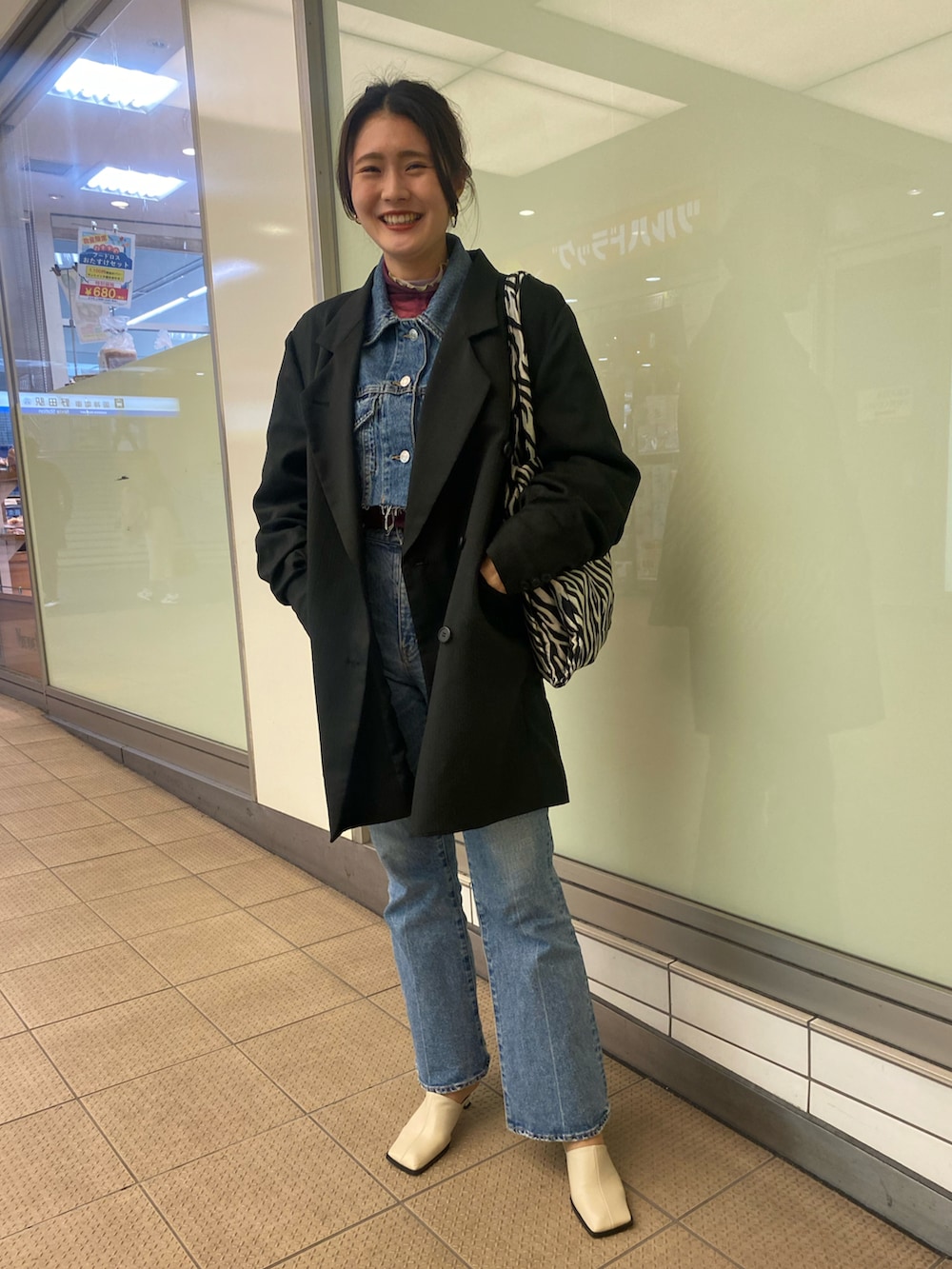 ブルー系のデニムジャケット、ブルー系のデニムパンツ、ブラック系のトートバッグを着用したレディースの春コーディネートの2枚目の写真