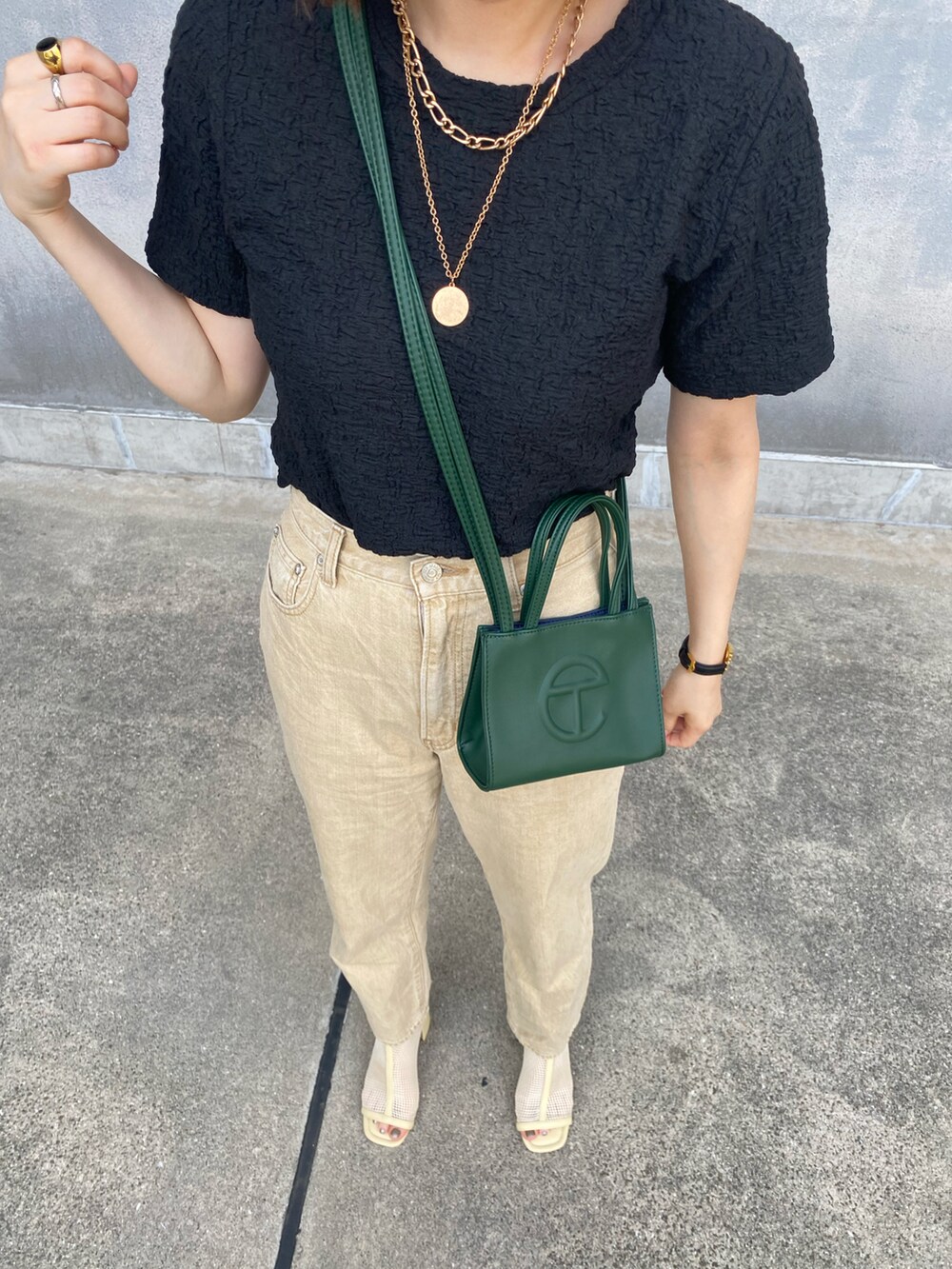 ブラック系のTシャツ/カットソー、グリーン系のバッグ、ベージュ系のデニムパンツを着用したレディースの春コーディネートの3枚目の写真