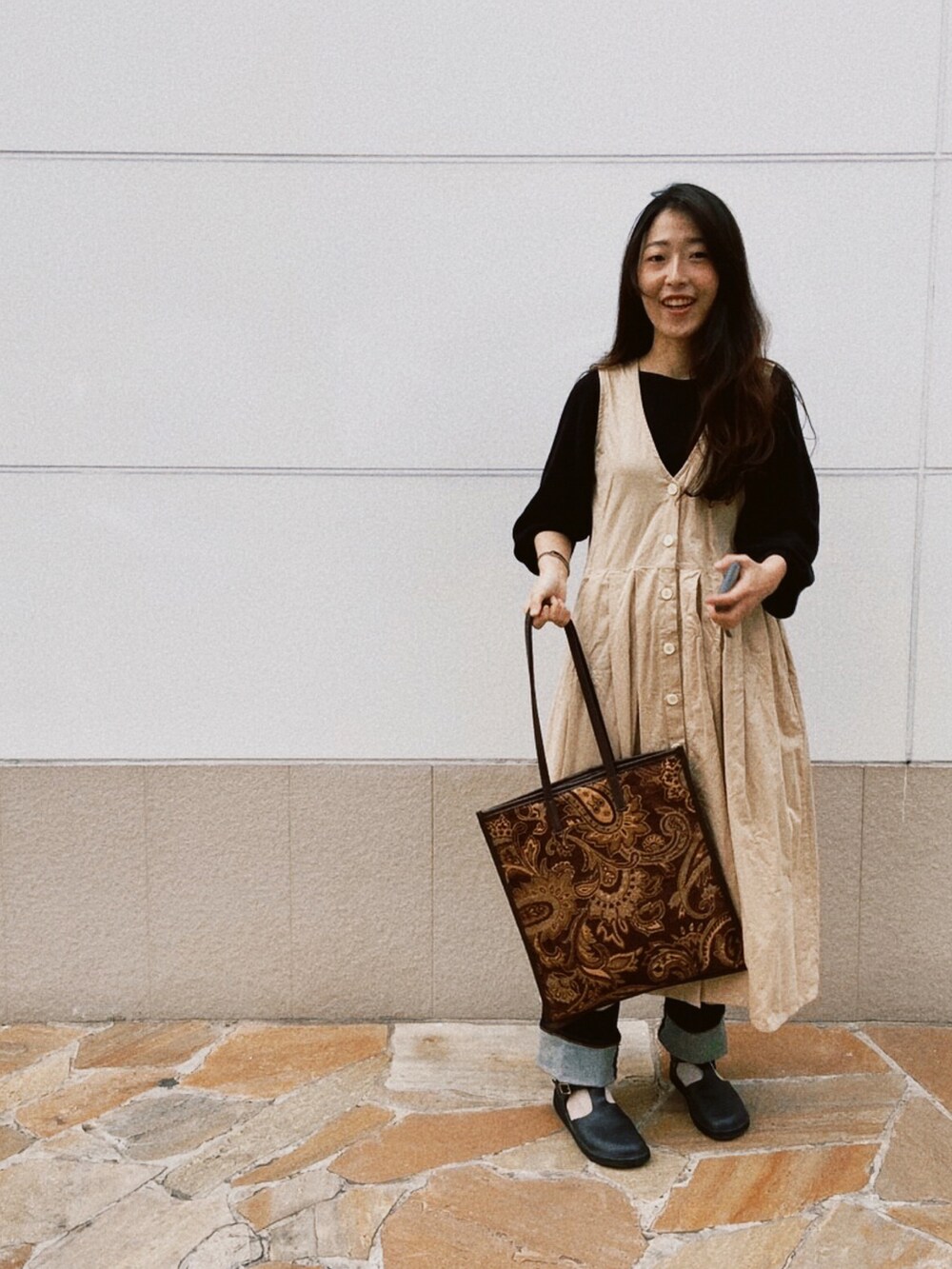 ベージュ系のジャンパースカート、ブルー系のシューズ、ブラウン系のショルダーバッグを着用したレディースの冬コーディネートの2枚目の写真