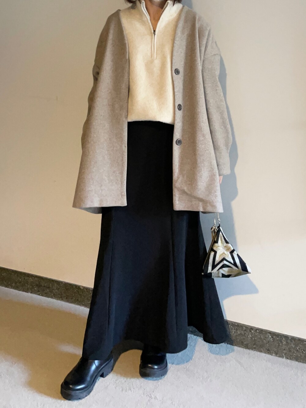 ブラック系のスカート、ブラック系のハンドバッグ、ブラック系のブーツを着用したレディースの冬コーディネートの2枚目の写真