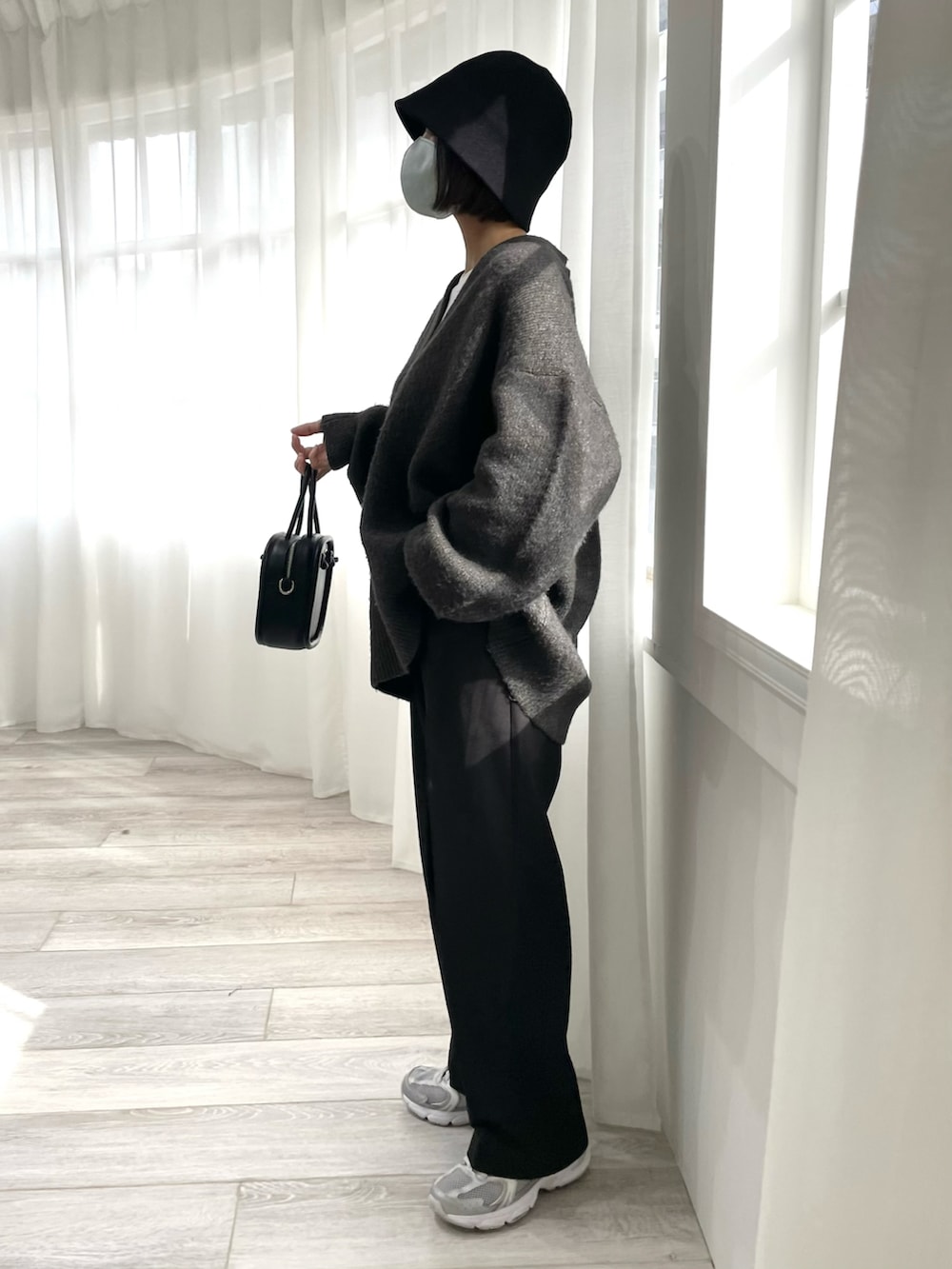 グレー系のニット/セーター、ブラック系のスラックス、シルバー系のスニーカーを着用したレディースの冬コーディネートの2枚目の写真