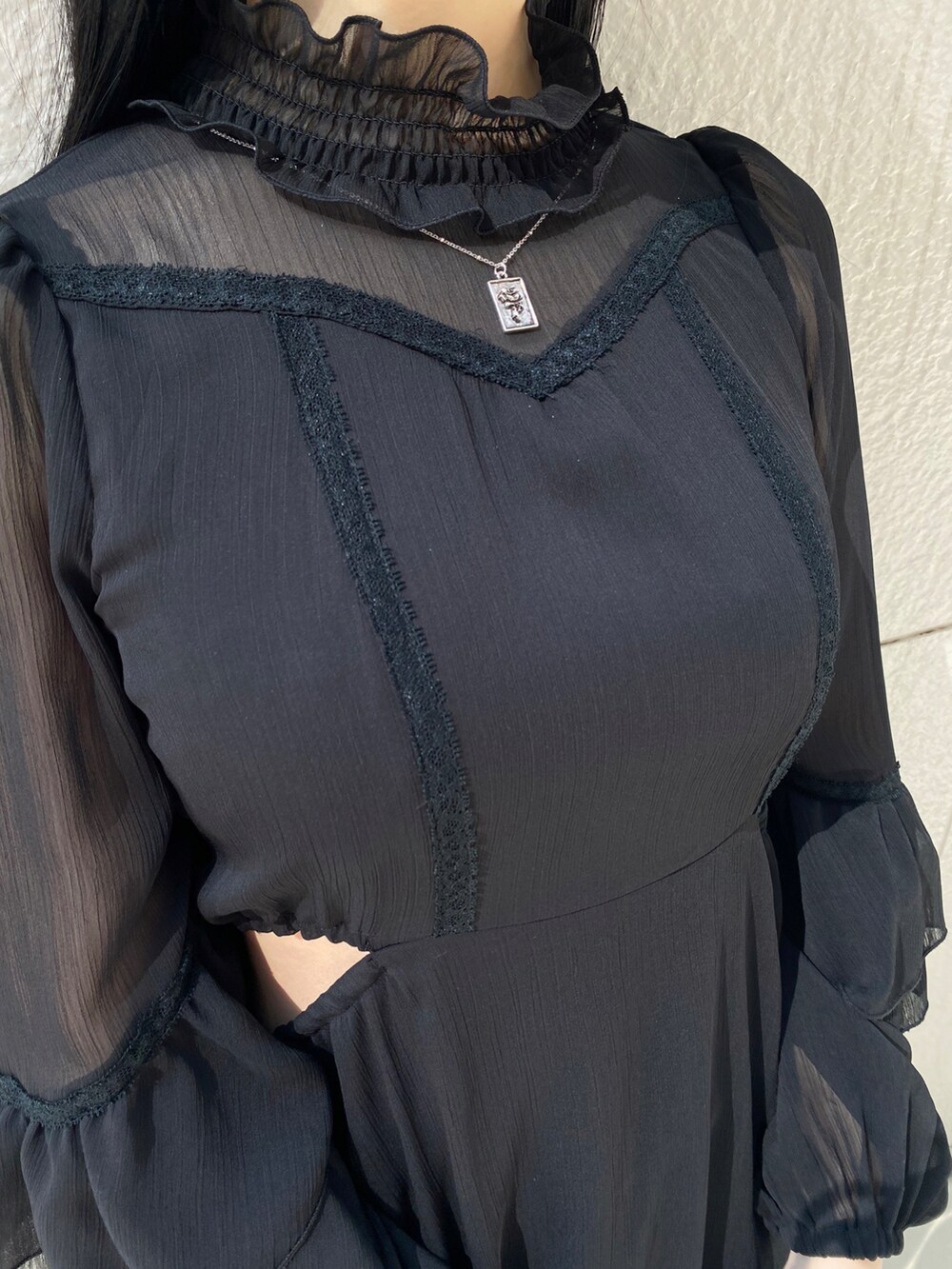 ブラック系のパンプス、ブラック系のワンピース、シルバー系のネックレスを着用したレディースの春コーディネートの4枚目の写真