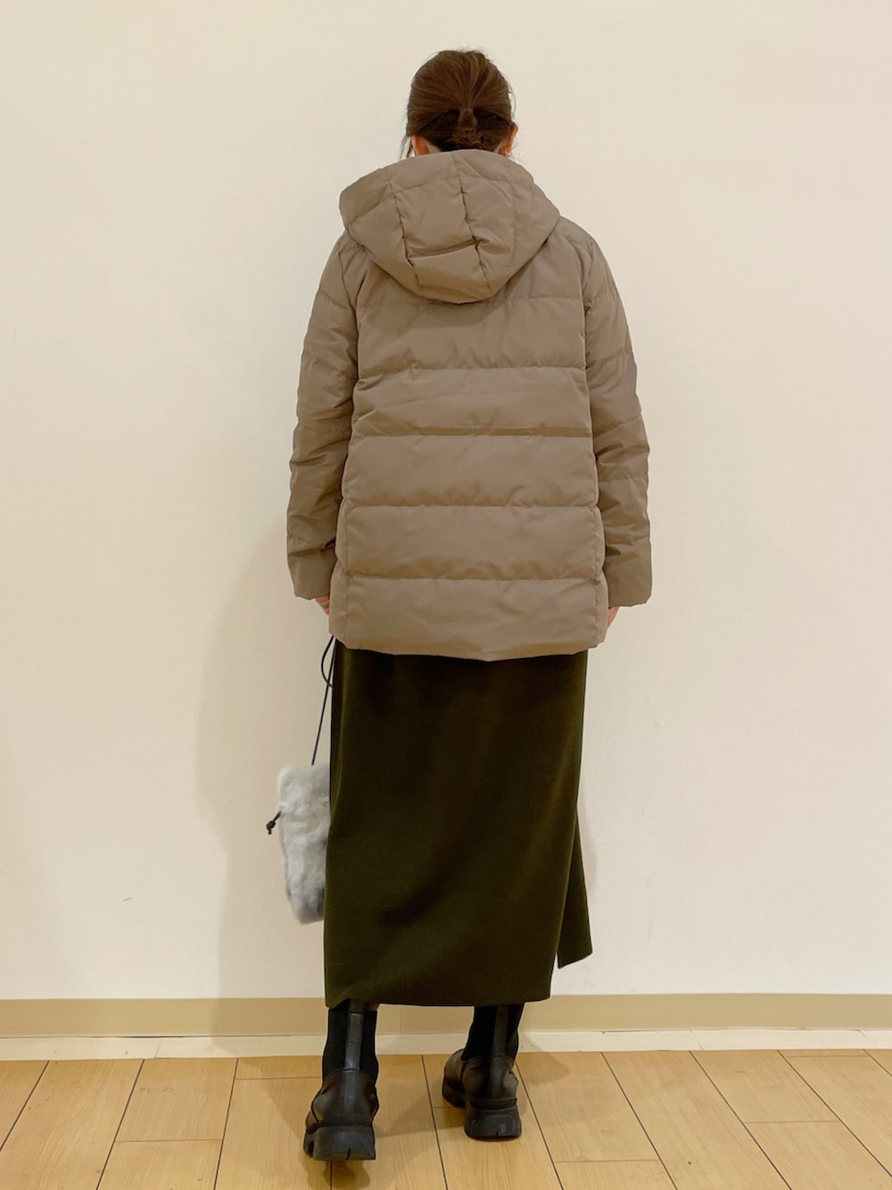 ベージュ系のダウンジャケット/コート、グリーン系のワンピース、グレー系のショルダーバッグを着用したレディースの秋コーディネートの2枚目の写真
