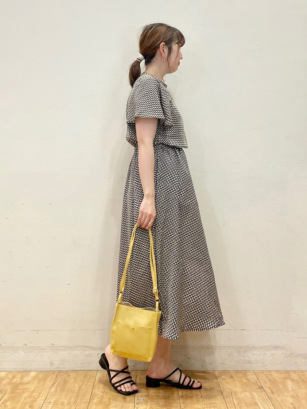 ブラック系のワンピース、イエロー系のショルダーバッグ、ブラック系のサンダルを着用したレディースの夏コーディネートの2枚目の写真