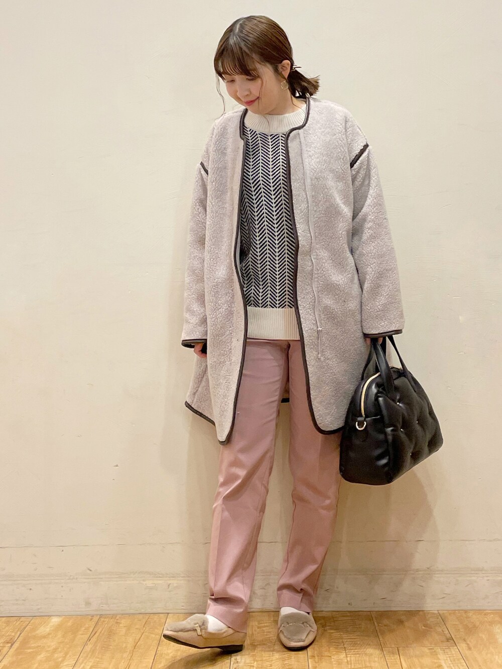 グレー系のノーカラーコート、ホワイト系のニット/セーター、ピンク系のその他パンツを着用したレディースの冬コーディネートの2枚目の写真
