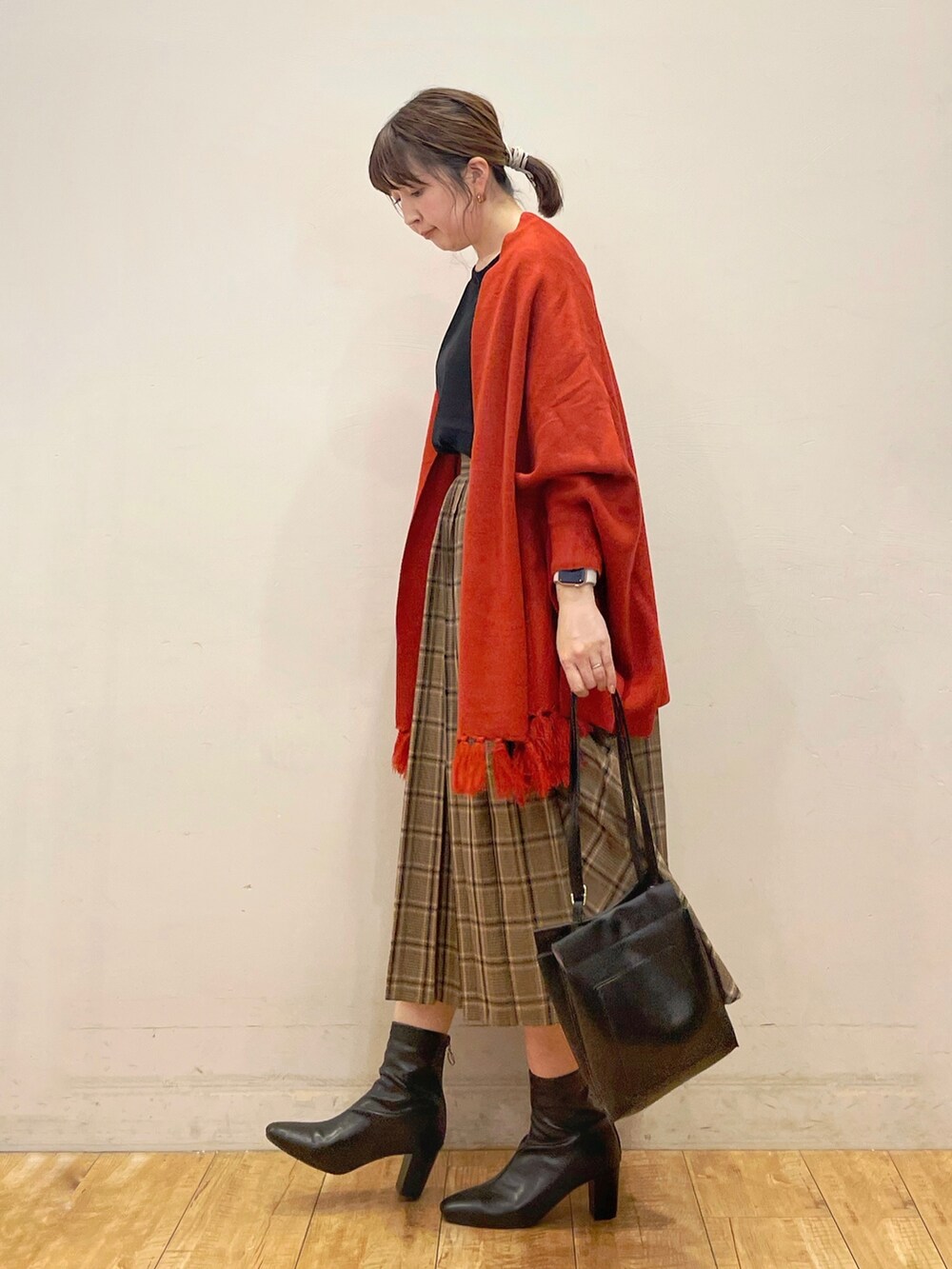 ブラック系のシャツ/ブラウス、オレンジ系のポンチョ、ベージュ系のスカートを着用したレディースの秋コーディネートの2枚目の写真
