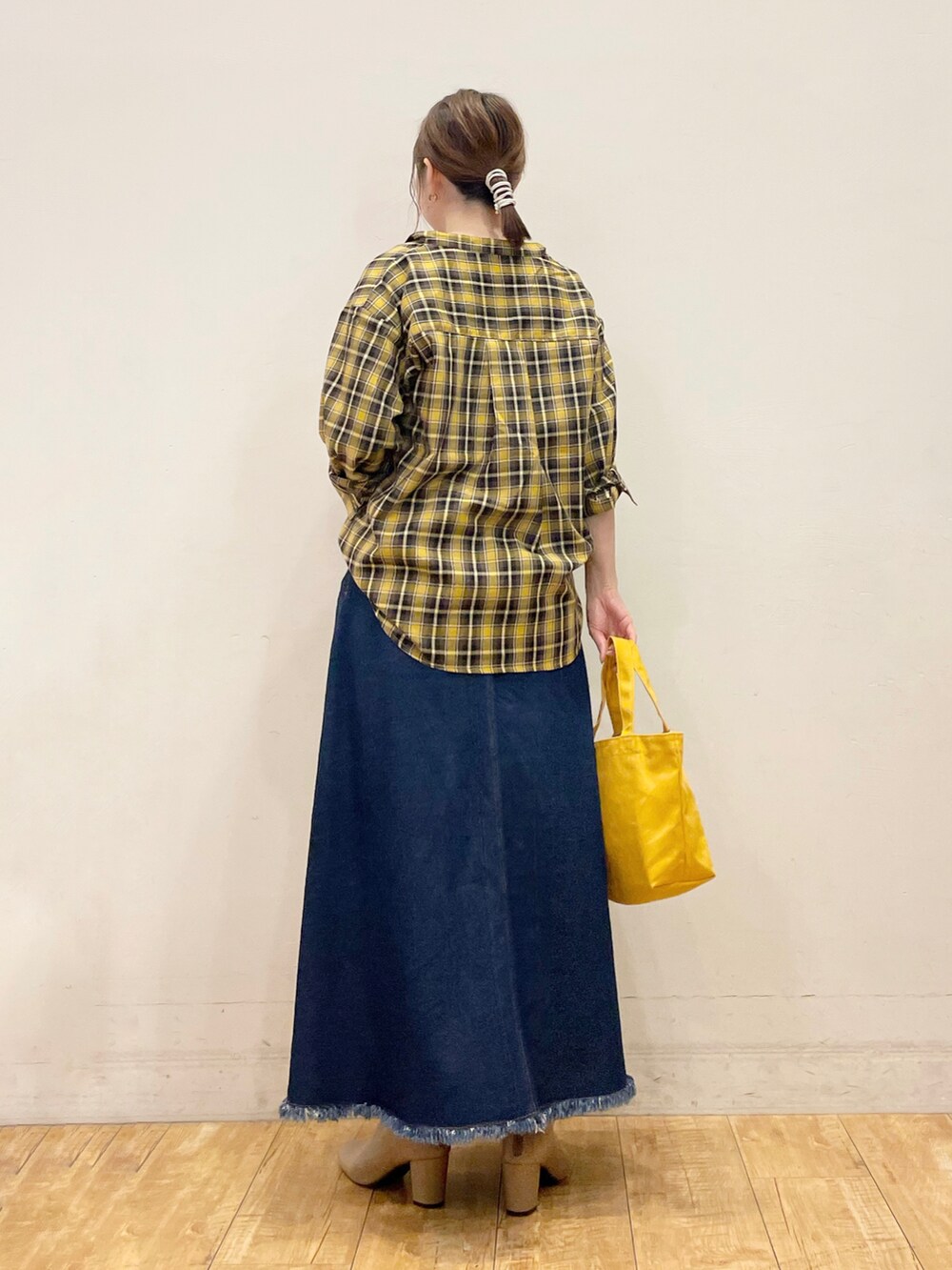 イエロー系のシャツ/ブラウス、ベージュ系のタンクトップ、ブルー系のデニムスカートを着用したレディースの秋コーディネートの3枚目の写真