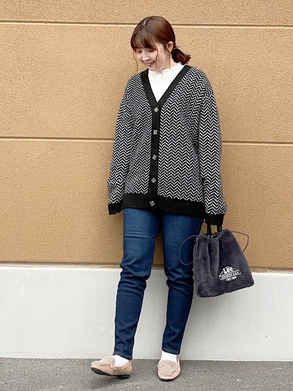 ブラック系のカーディガン/ボレロ、ホワイト系のニット/セーター、ブルー系のデニムパンツを着用したレディースの冬コーディネートの2枚目の写真