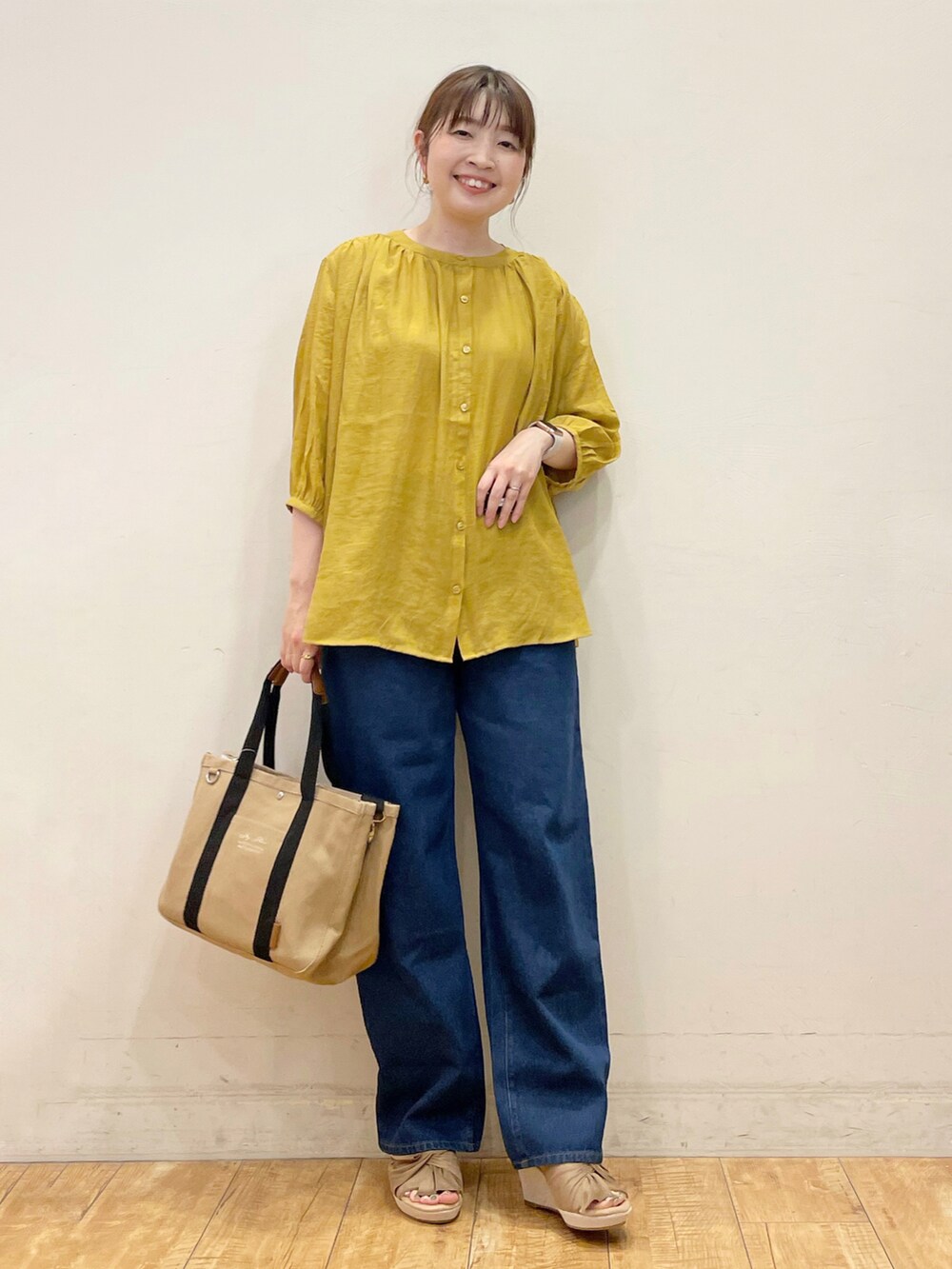 イエロー系のシャツ/ブラウス、ブルー系のデニムパンツ、ブラウン系のトートバッグを着用したレディースの夏コーディネートの2枚目の写真