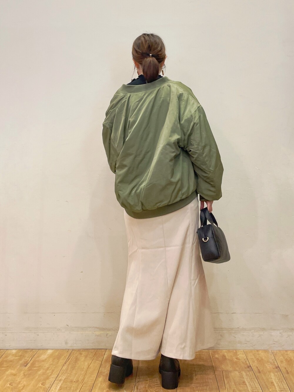 ブラック系のTシャツ/カットソー、ホワイト系のスカート、ブラック系のショルダーバッグを着用したレディースの秋コーディネートの3枚目の写真