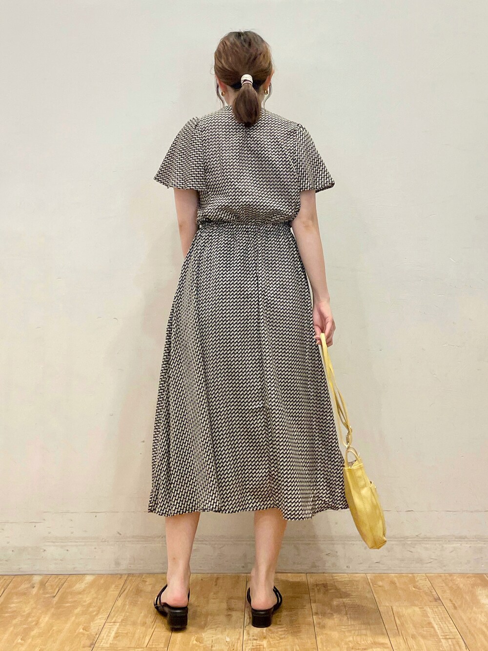 ブラック系のワンピース、イエロー系のショルダーバッグ、ブラック系のサンダルを着用したレディースの夏コーディネートの3枚目の写真