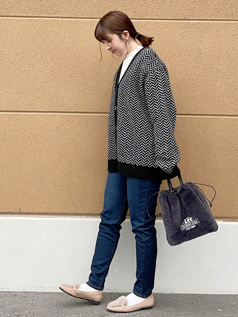 ブラック系のカーディガン/ボレロ、ホワイト系のニット/セーター、ブルー系のデニムパンツを着用したレディースの冬コーディネートの3枚目の写真