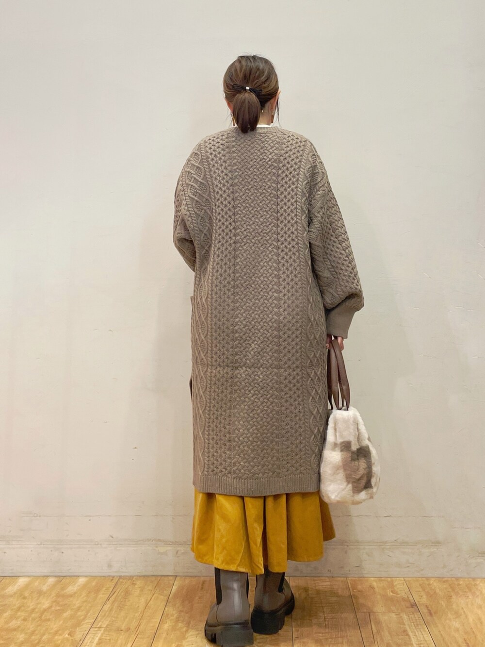 ベージュ系のカーディガン/ボレロ、ホワイト系のTシャツ/カットソー、イエロー系のスカートを着用したレディースの秋コーディネートの3枚目の写真