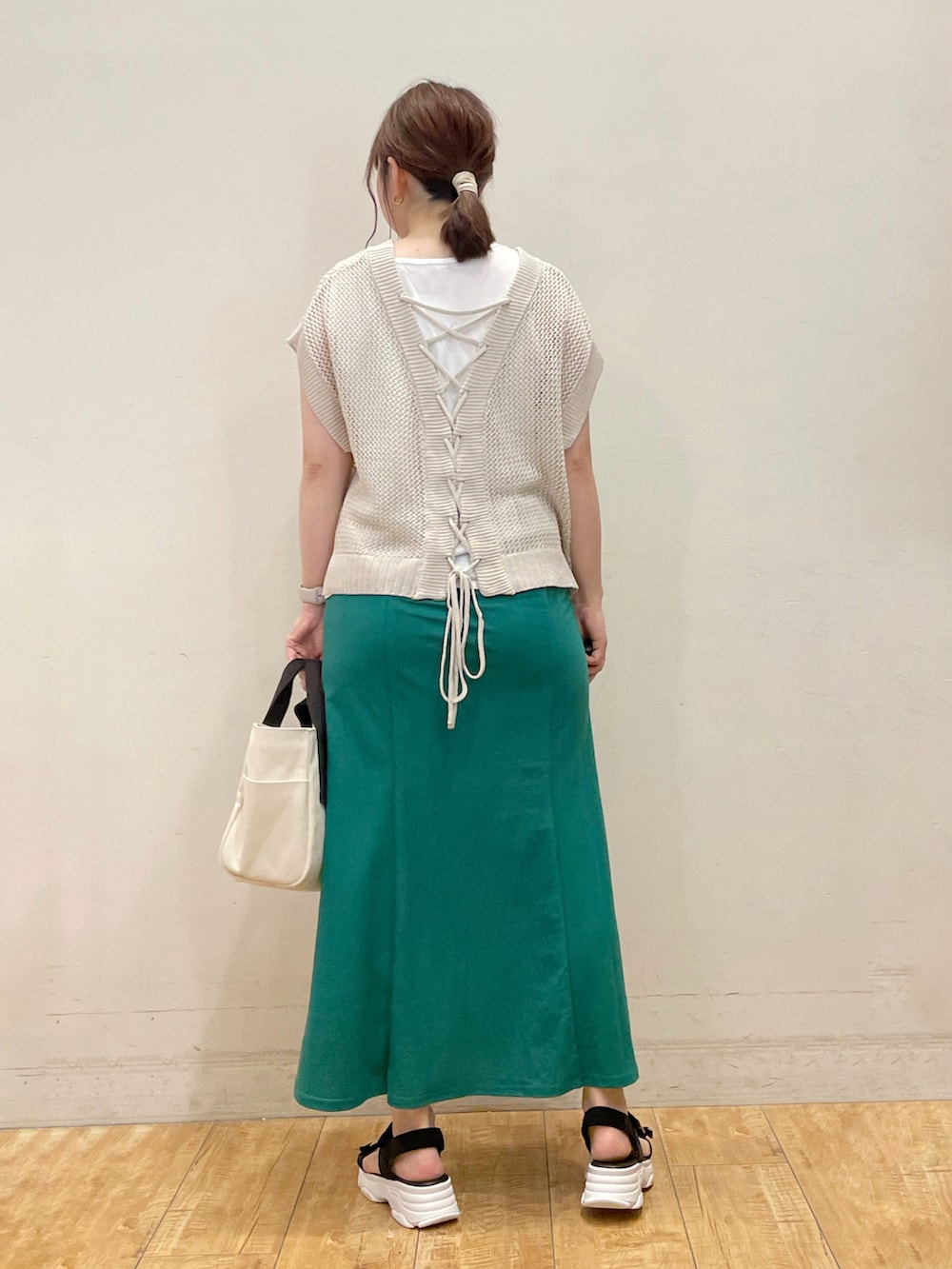 ベージュ系のニット/セーター、グリーン系のスカート、ベージュ系のトートバッグを着用したレディースの夏コーディネートの2枚目の写真