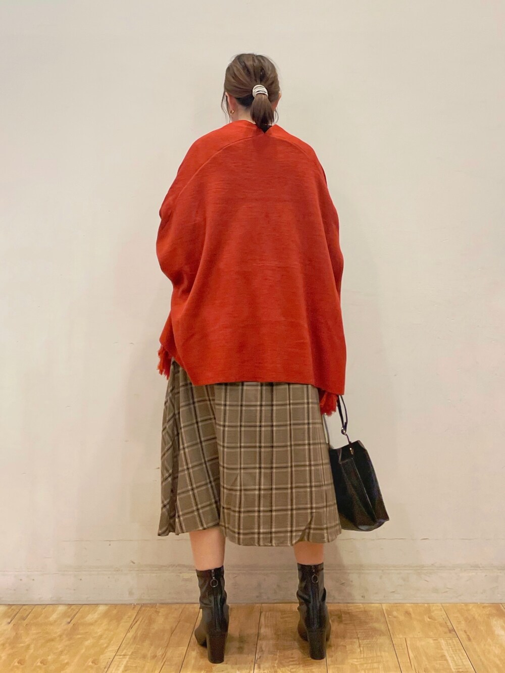 ブラック系のシャツ/ブラウス、オレンジ系のポンチョ、ベージュ系のスカートを着用したレディースの秋コーディネートの3枚目の写真