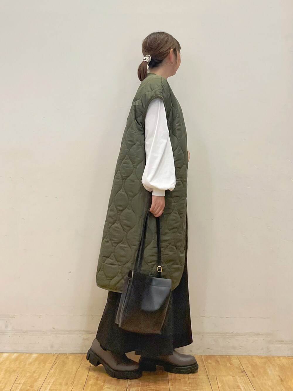 グリーン系のノーカラーコート、ホワイト系のTシャツ/カットソー、ブラック系のスカートを着用したレディースの秋コーディネートの2枚目の写真