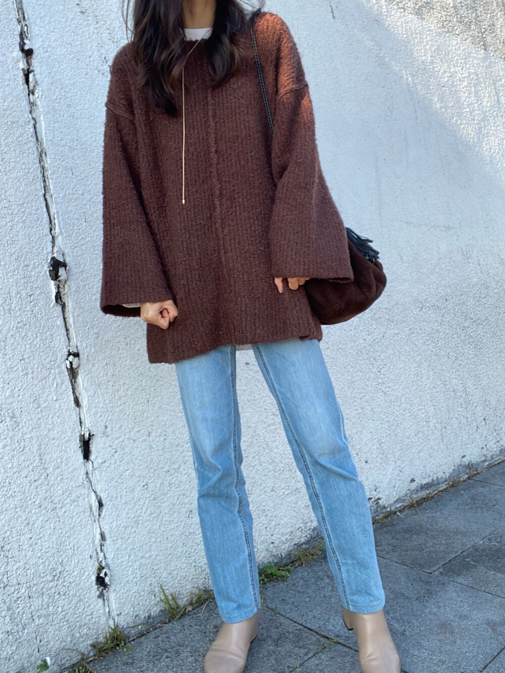 ブラウン系のニット/セーター、ブルー系のデニムパンツ、ベージュ系のブーツを着用したレディースの冬コーディネートの3枚目の写真