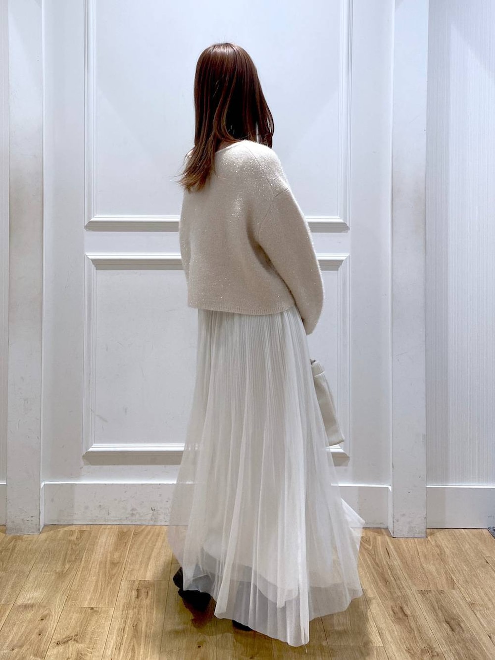 ホワイト系のスカート、ホワイト系のニット/セーター、ブラック系のブーツを着用したレディースの春コーディネートの5枚目の写真