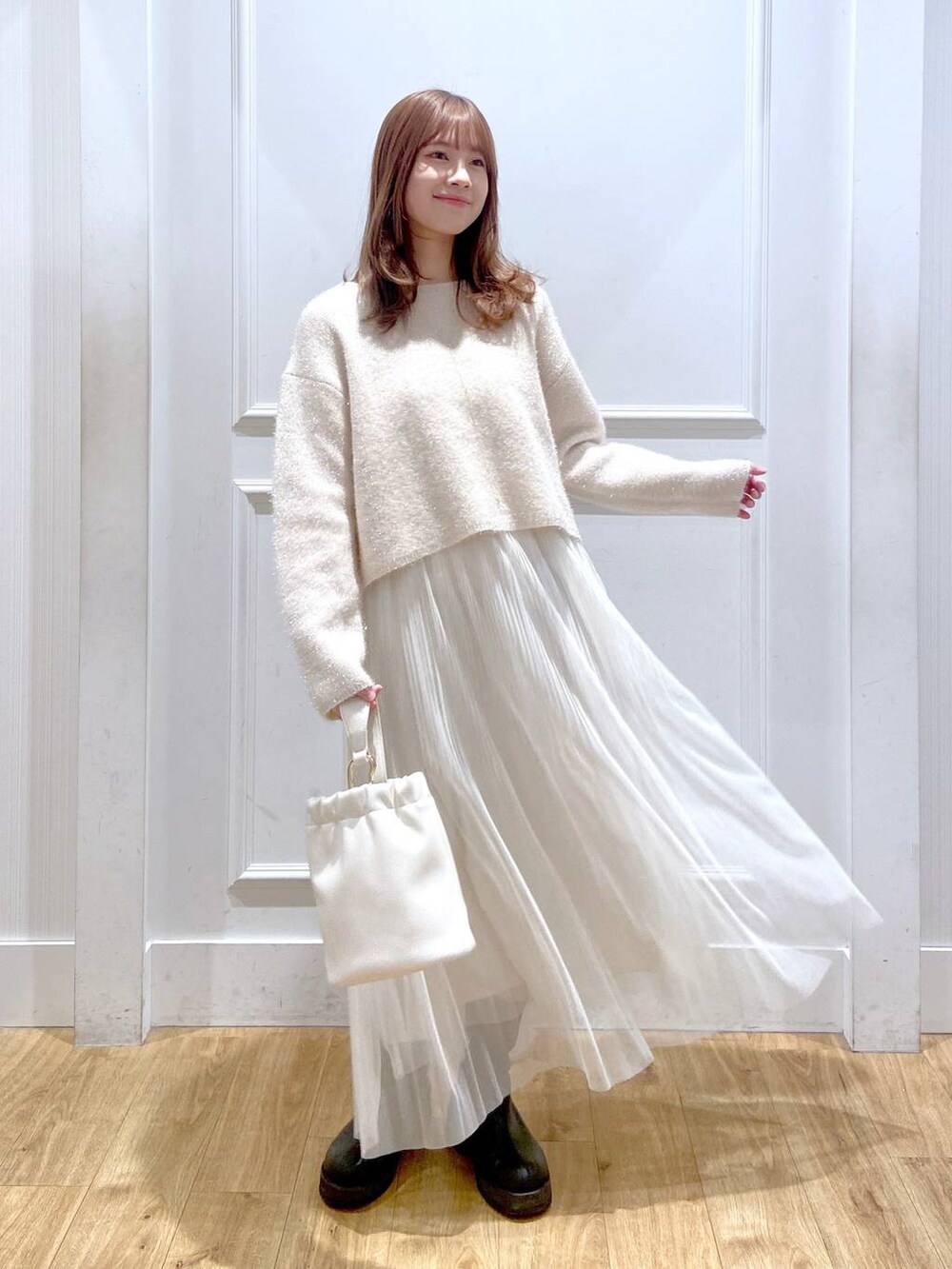 ホワイト系のスカート、ホワイト系のニット/セーター、ブラック系のブーツを着用したレディースの春コーディネートの4枚目の写真