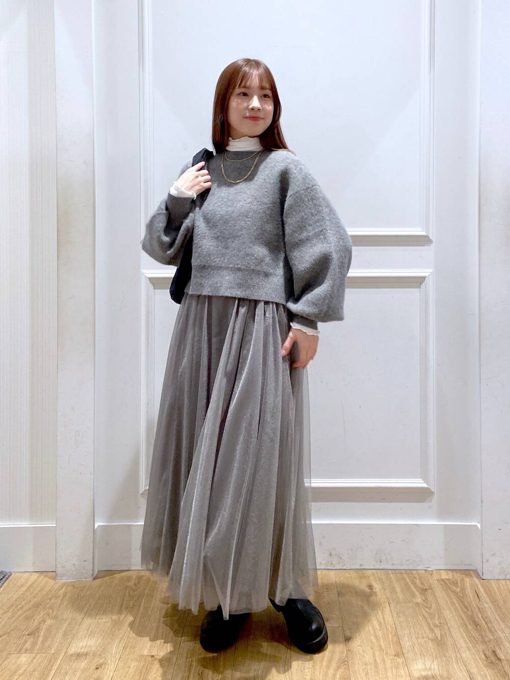 ホワイト系のTシャツ/カットソー、グレー系のカーディガン/ボレロ、ブラック系のブーツを着用したレディースの冬コーディネートの4枚目の写真