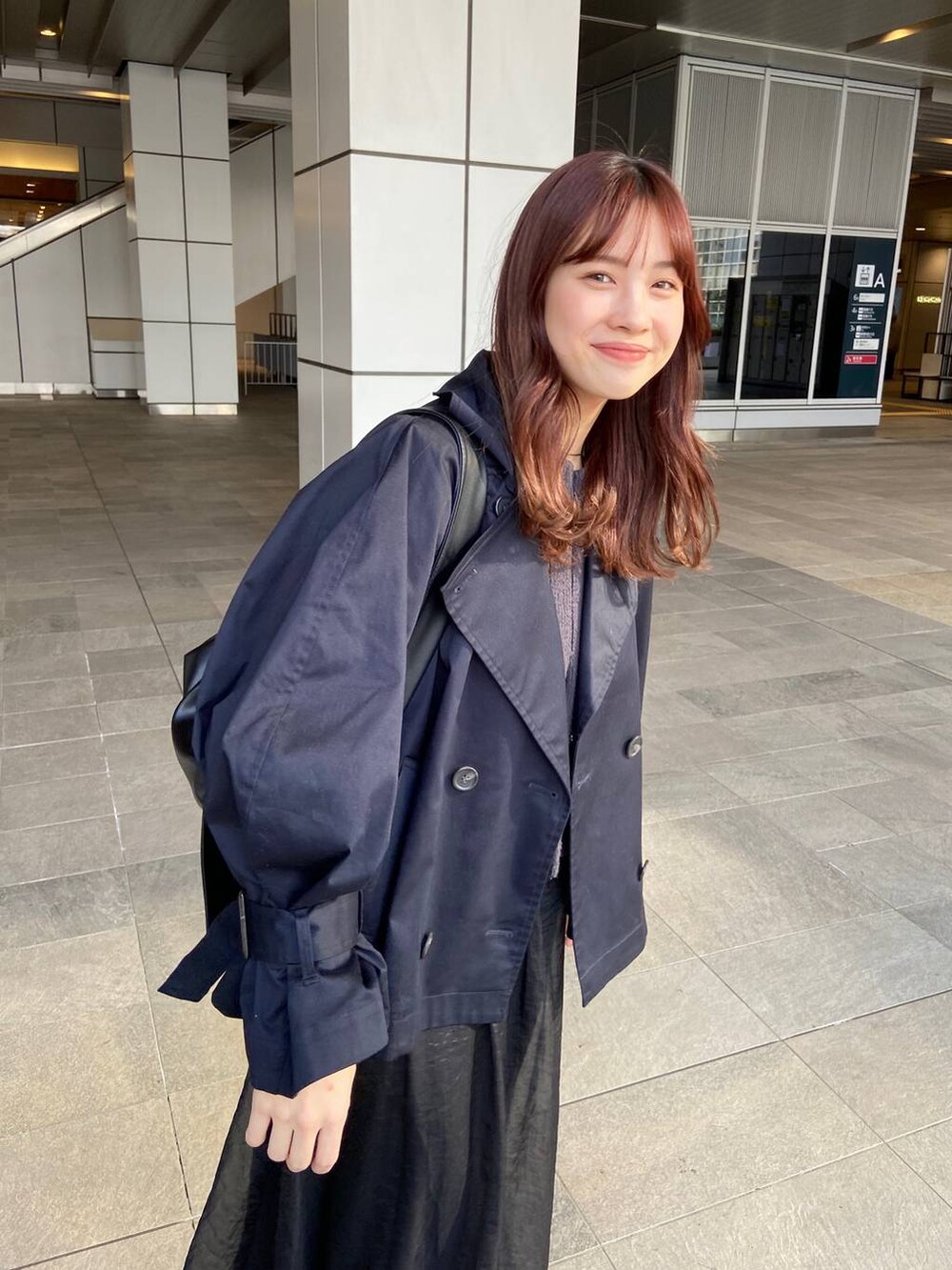 ブラック系のショルダーバッグ、ブルー系のトレンチコート、グレー系のカーディガン/ボレロを着用したレディースの春コーディネートの2枚目の写真