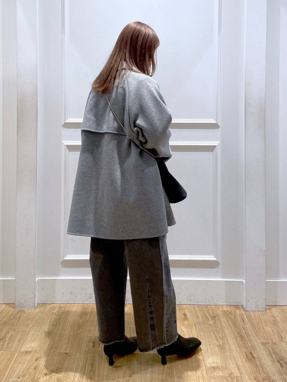 グレー系のステンカラーコート、ブラック系のブーツ、ホワイト系のTシャツ/カットソーを着用したレディースの冬コーディネートの5枚目の写真