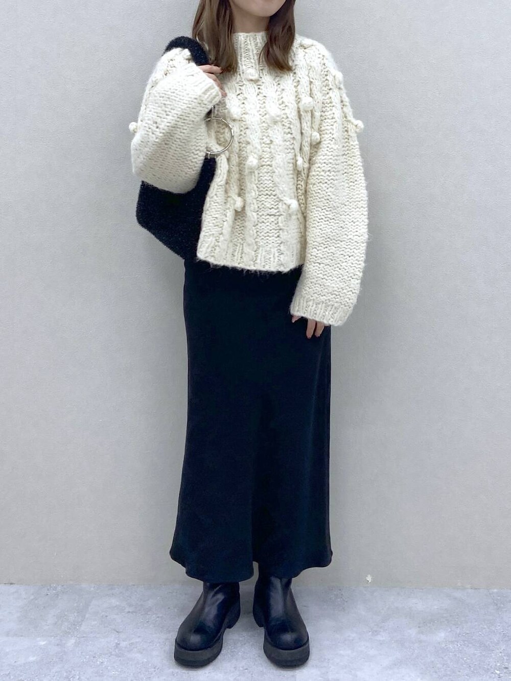 ホワイト系のニット/セーター、ブラック系のブーツ、ブラック系のクラッチバッグを着用したレディースの冬コーディネートの5枚目の写真