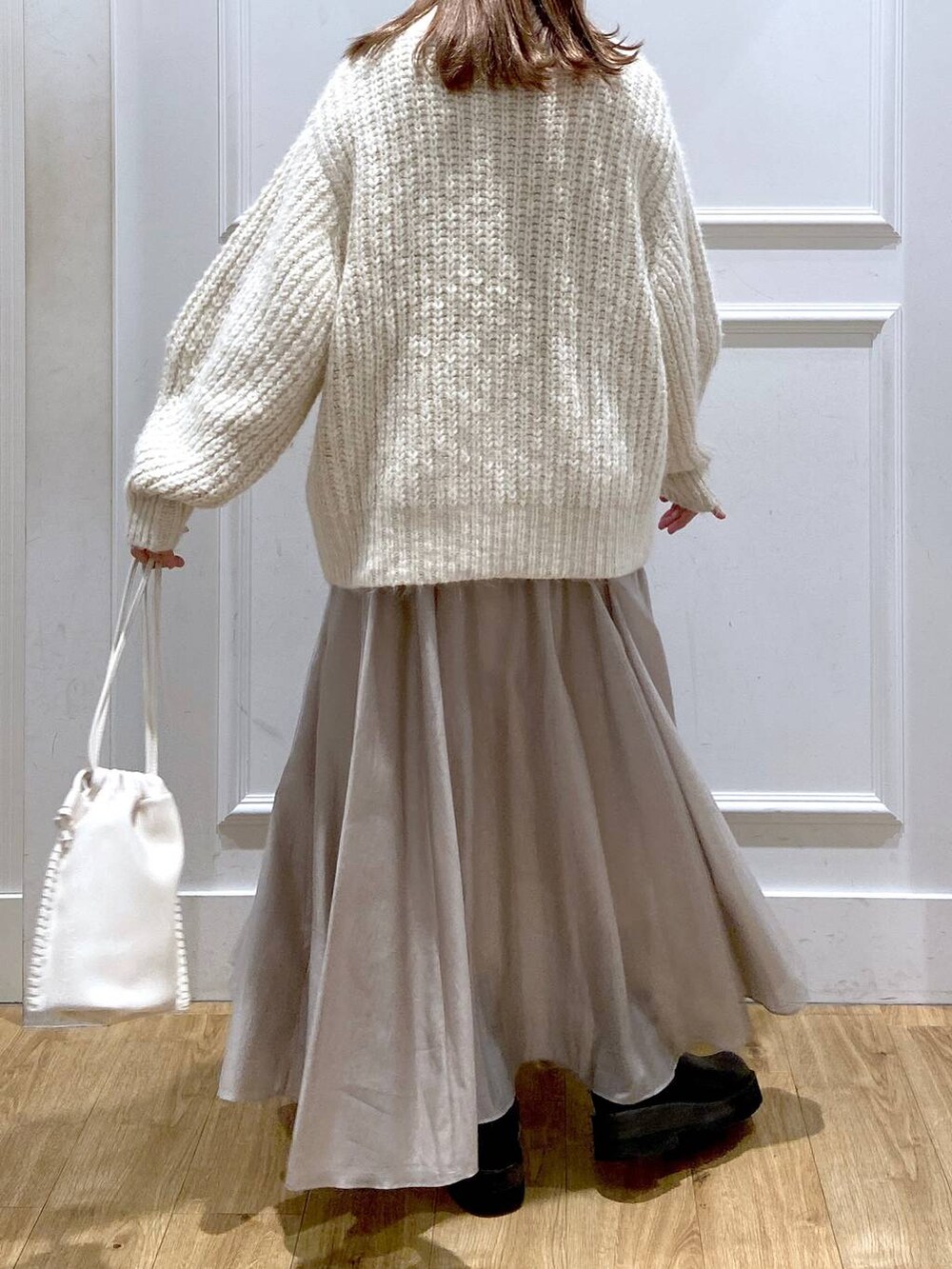 ホワイト系のショルダーバッグ、ホワイト系のニット/セーター、ブラック系のブーツを着用したレディースの春コーディネートの4枚目の写真