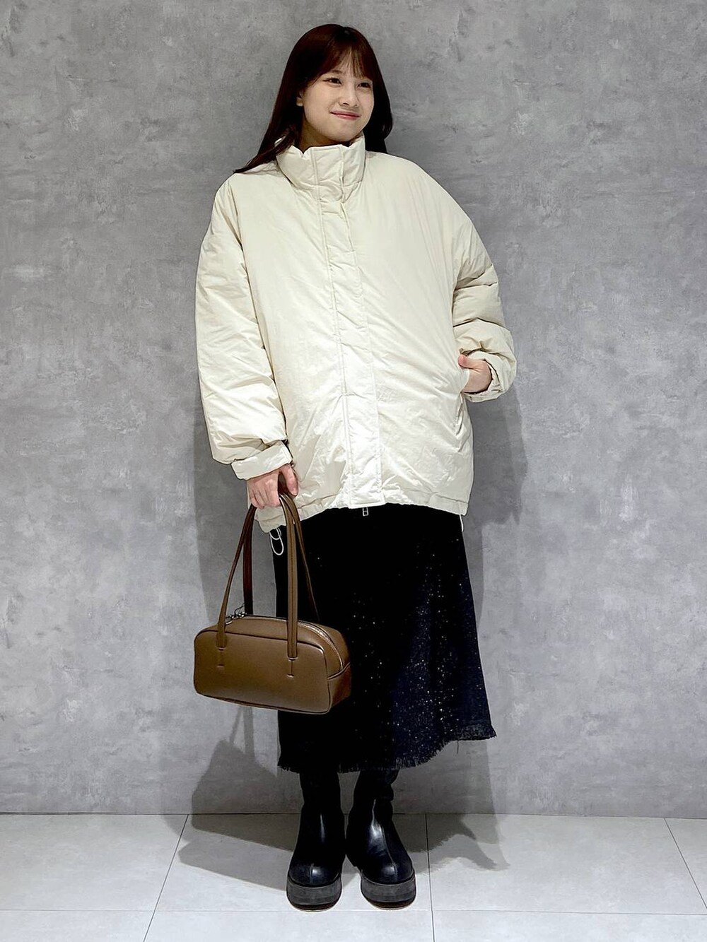 ホワイト系のダウンジャケット/コート、グレー系のスカート、ブラック系のブーツを着用したレディースの冬コーディネートの3枚目の写真