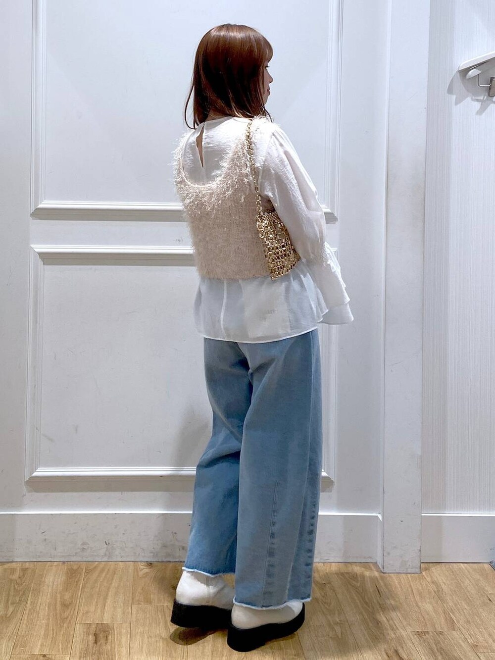 ホワイト系のブーツ、ブルー系のデニムパンツ、ゴールド系のショルダーバッグを着用したレディースの冬コーディネートの4枚目の写真