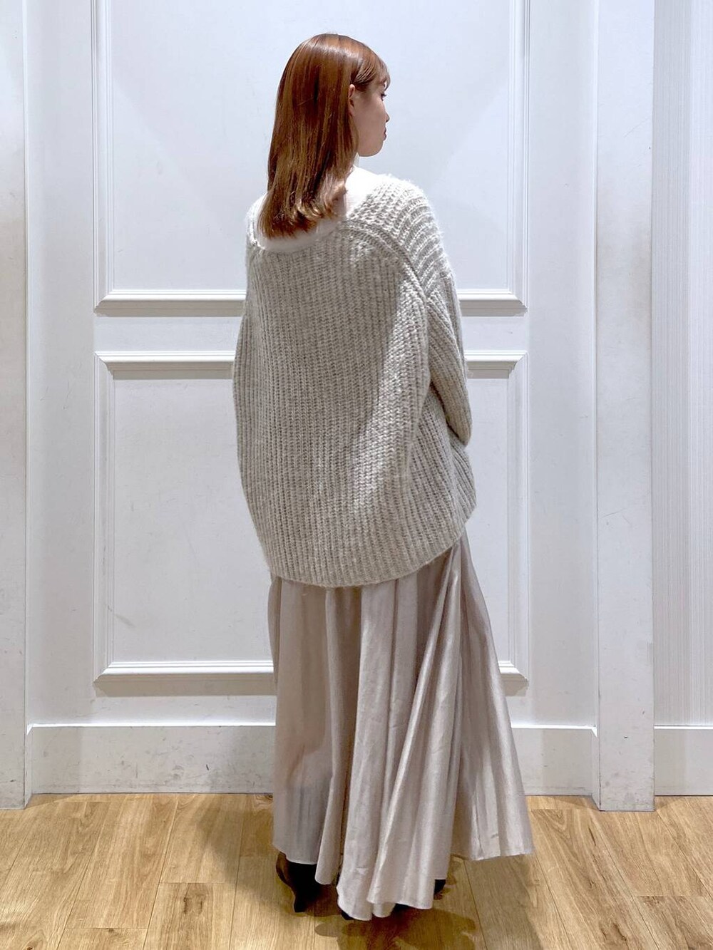 ホワイト系のショルダーバッグ、ベージュ系のスカート、ブラック系のブーツを着用したレディースの冬コーディネートの3枚目の写真