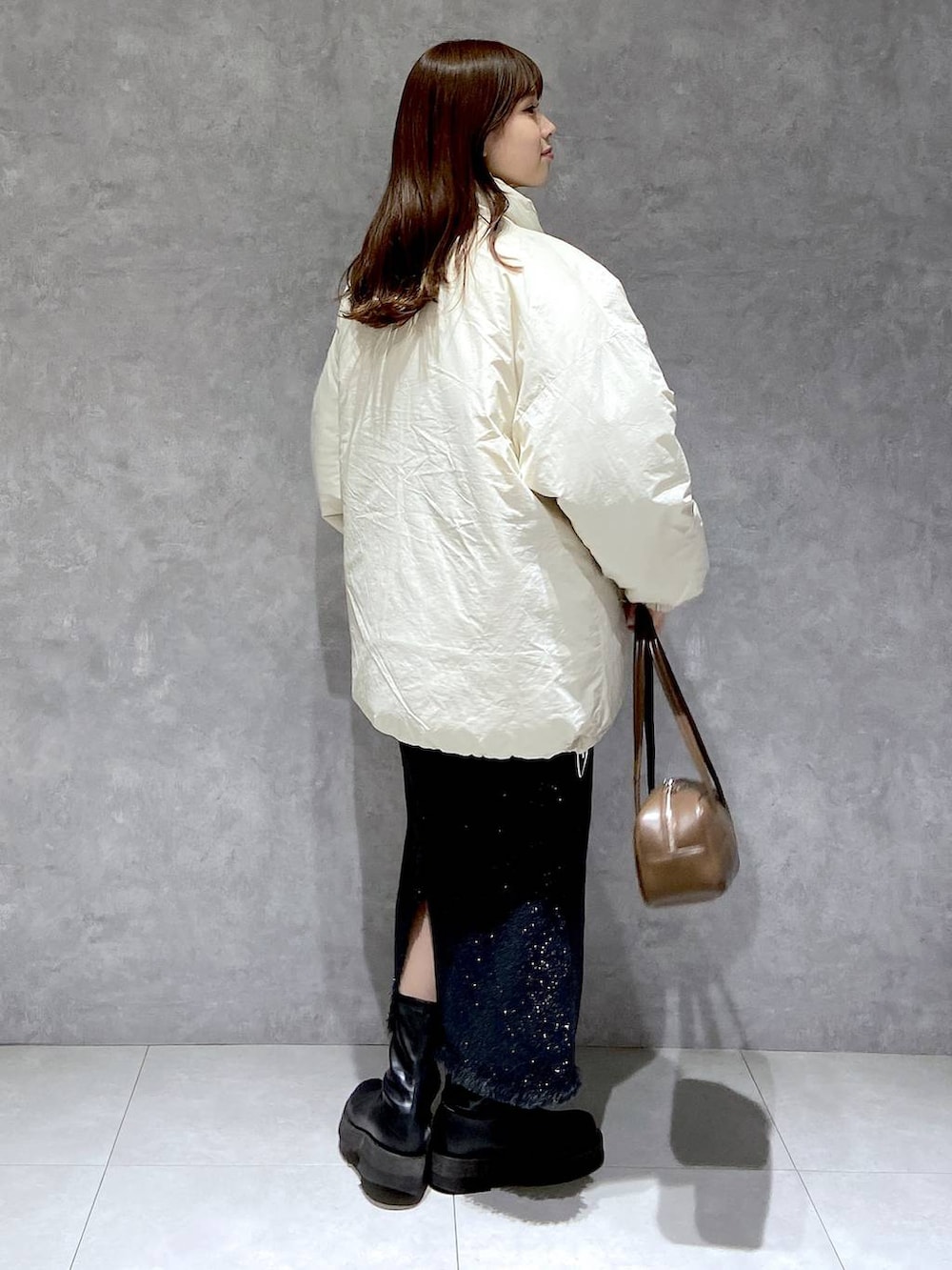 ホワイト系のダウンジャケット/コート、グレー系のスカート、ブラック系のブーツを着用したレディースの冬コーディネートの5枚目の写真