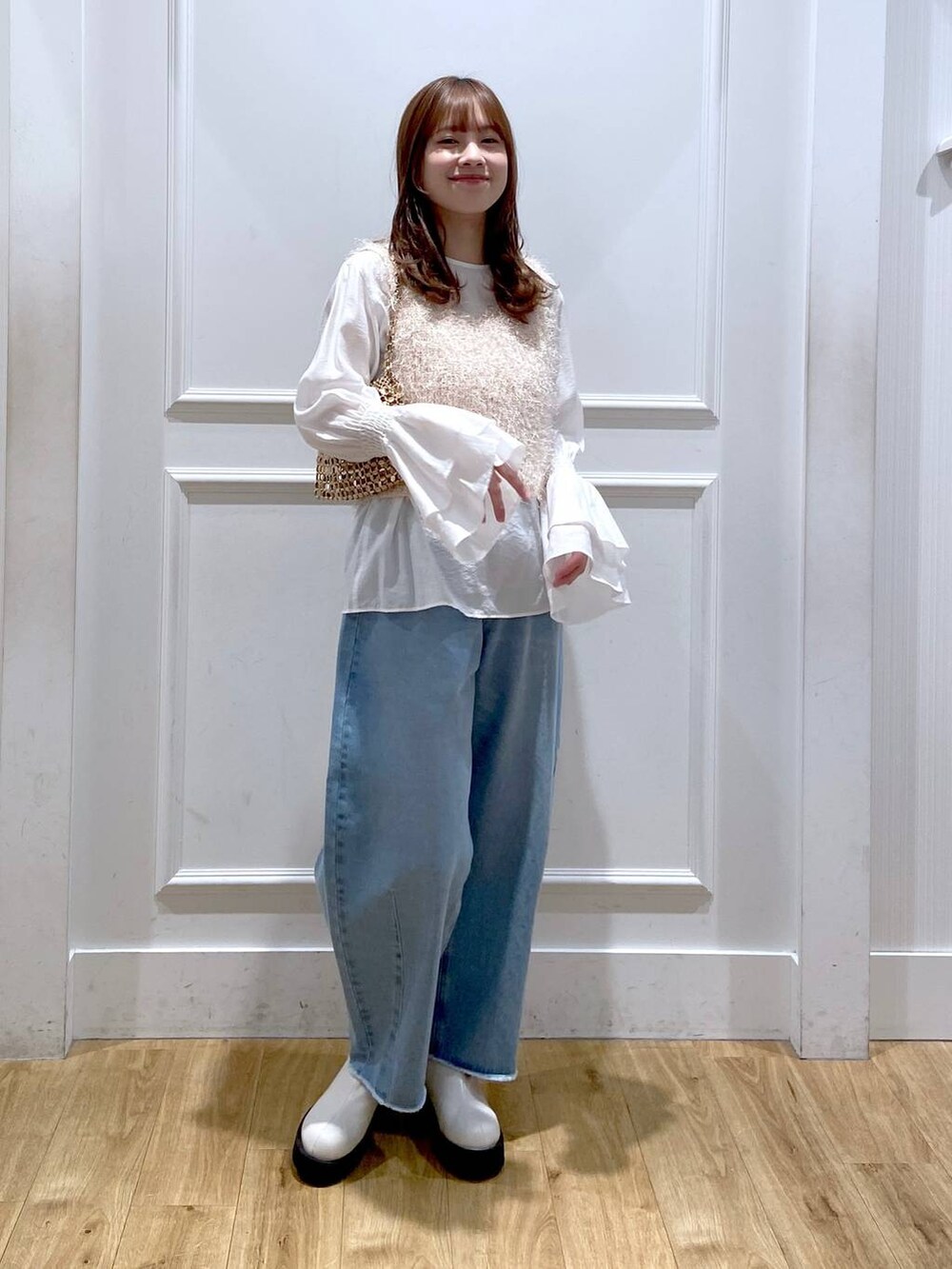 ホワイト系のブーツ、ブルー系のデニムパンツ、ゴールド系のショルダーバッグを着用したレディースの冬コーディネートの2枚目の写真