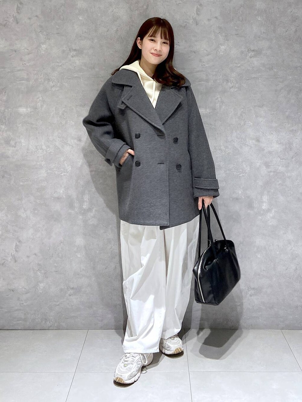 グレー系のピーコート、ホワイト系のその他パンツ、ブラック系のボストンバッグを着用したレディースの秋コーディネートの2枚目の写真