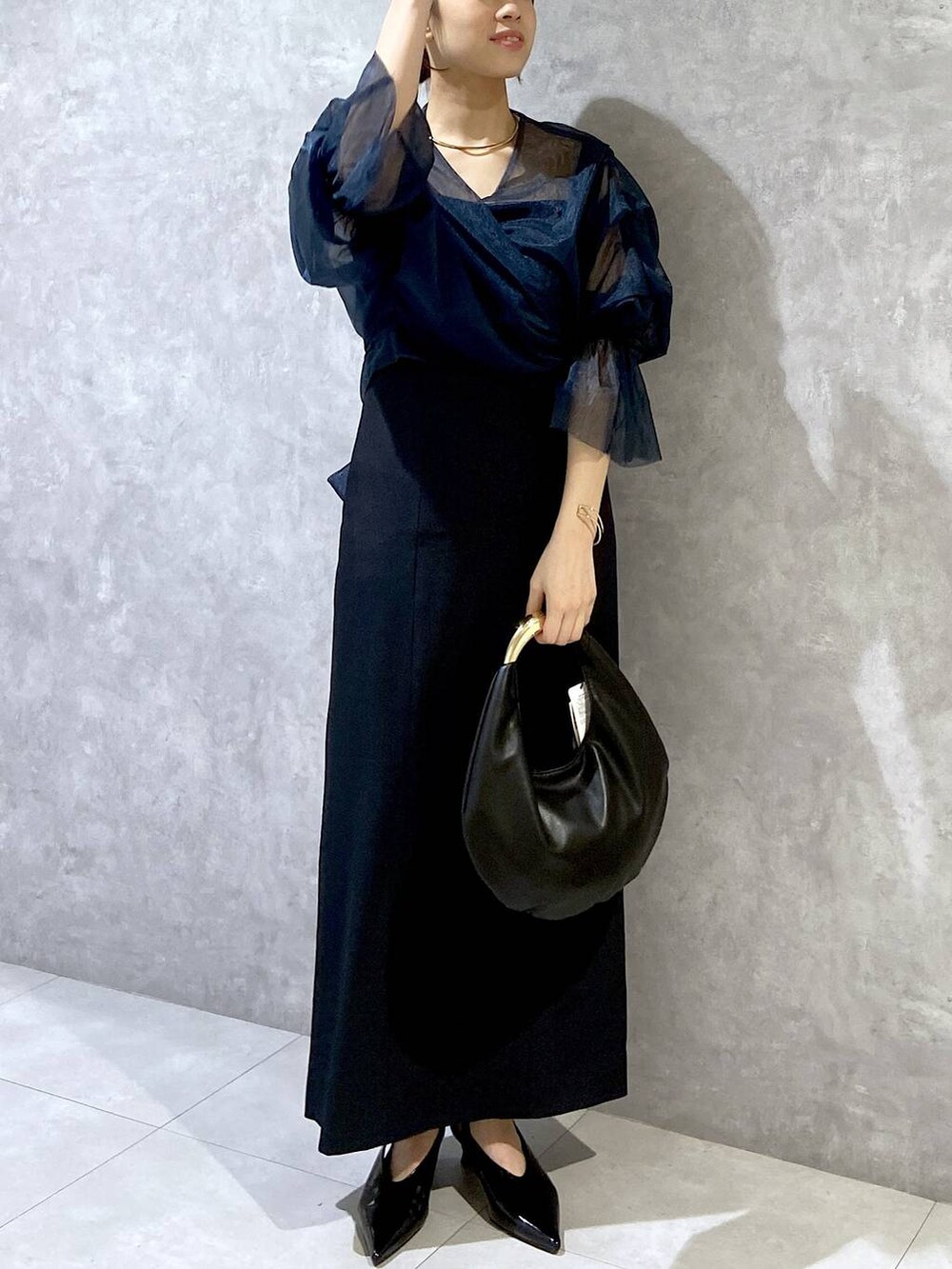 ブラック系のハンドバッグ、ブラック系のパンプス、ブルー系のドレスを着用したレディースの秋コーディネートの3枚目の写真