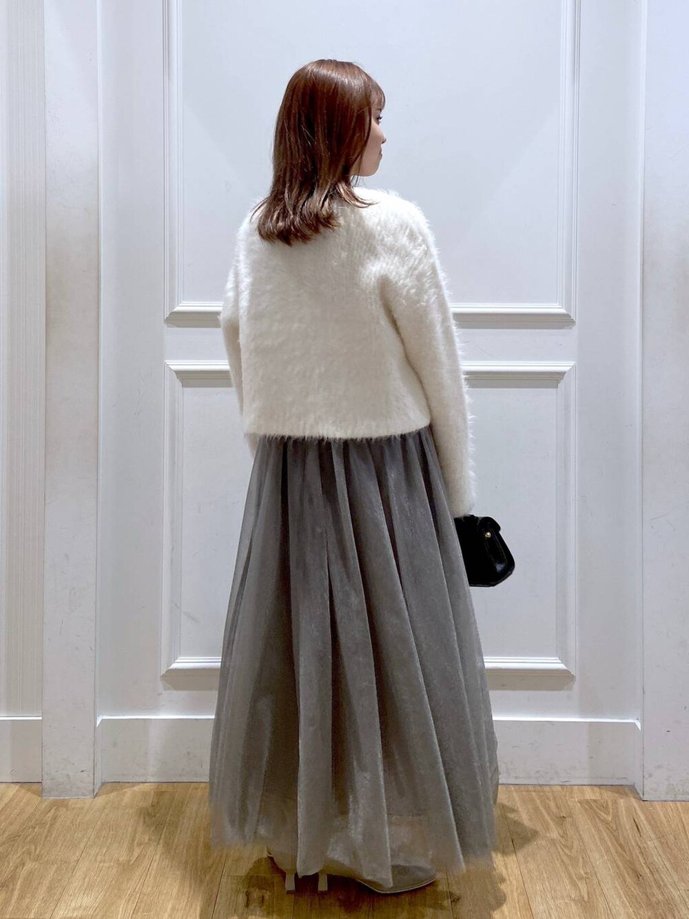 ホワイト系のカーディガン/ボレロ、ホワイト系のブーツ、ブラック系のショルダーバッグを着用したレディースの冬コーディネートの4枚目の写真