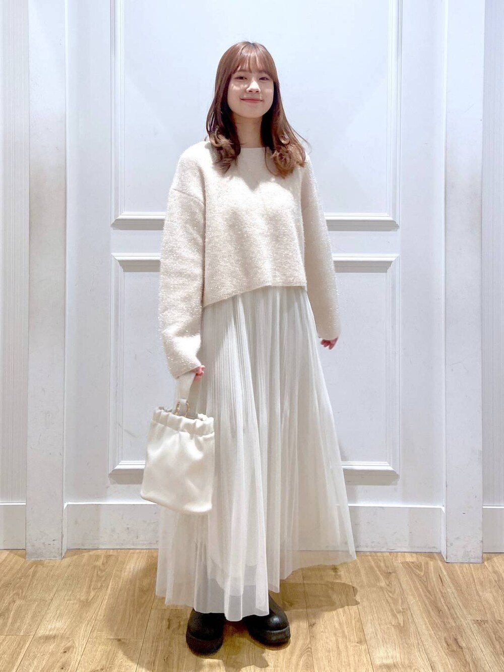 ホワイト系のスカート、ホワイト系のニット/セーター、ブラック系のブーツを着用したレディースの春コーディネートの2枚目の写真