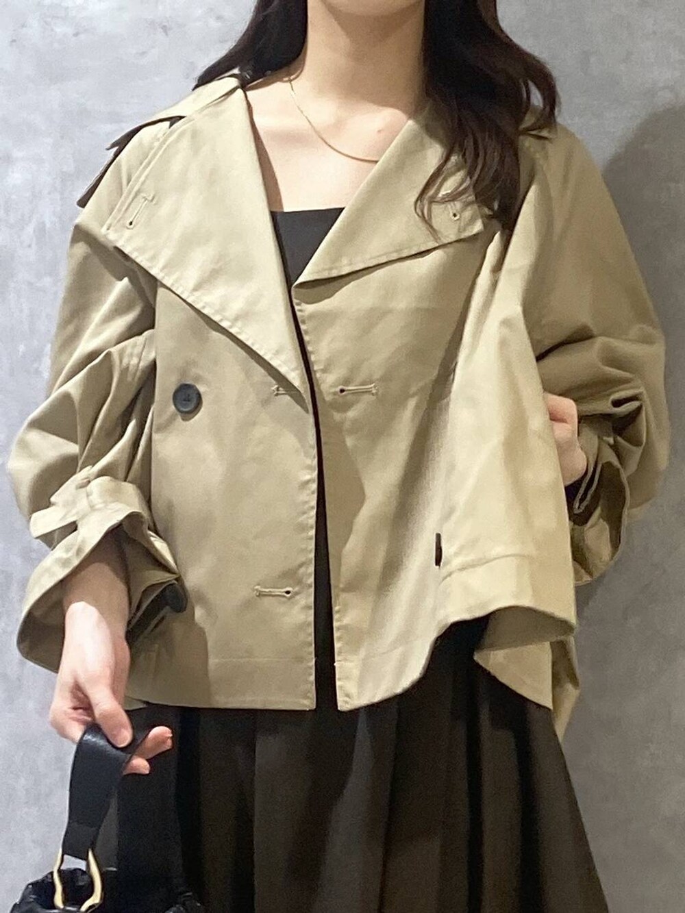 ブラウン系のジャンパースカート、ブラック系のショルダーバッグ、ベージュ系のトレンチコートを着用したレディースの秋コーディネートの7枚目の写真