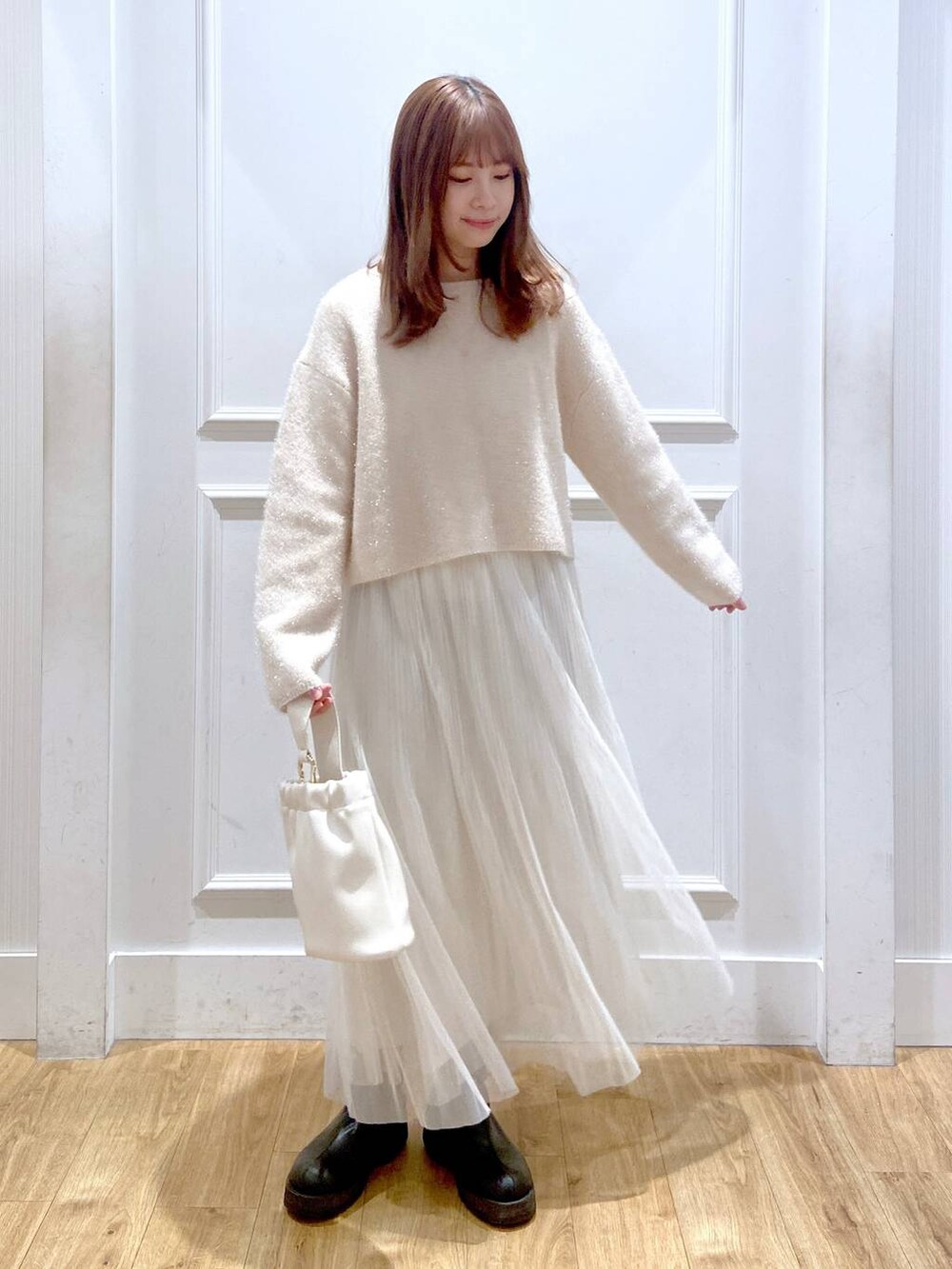 ホワイト系のスカート、ホワイト系のニット/セーター、ブラック系のブーツを着用したレディースの春コーディネートの3枚目の写真