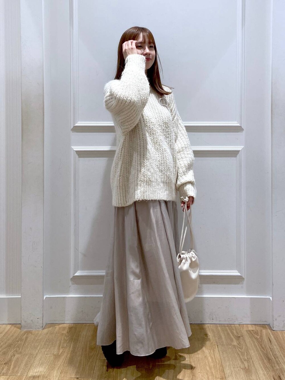 ホワイト系のショルダーバッグ、ホワイト系のニット/セーター、ブラック系のブーツを着用したレディースの春コーディネートの2枚目の写真