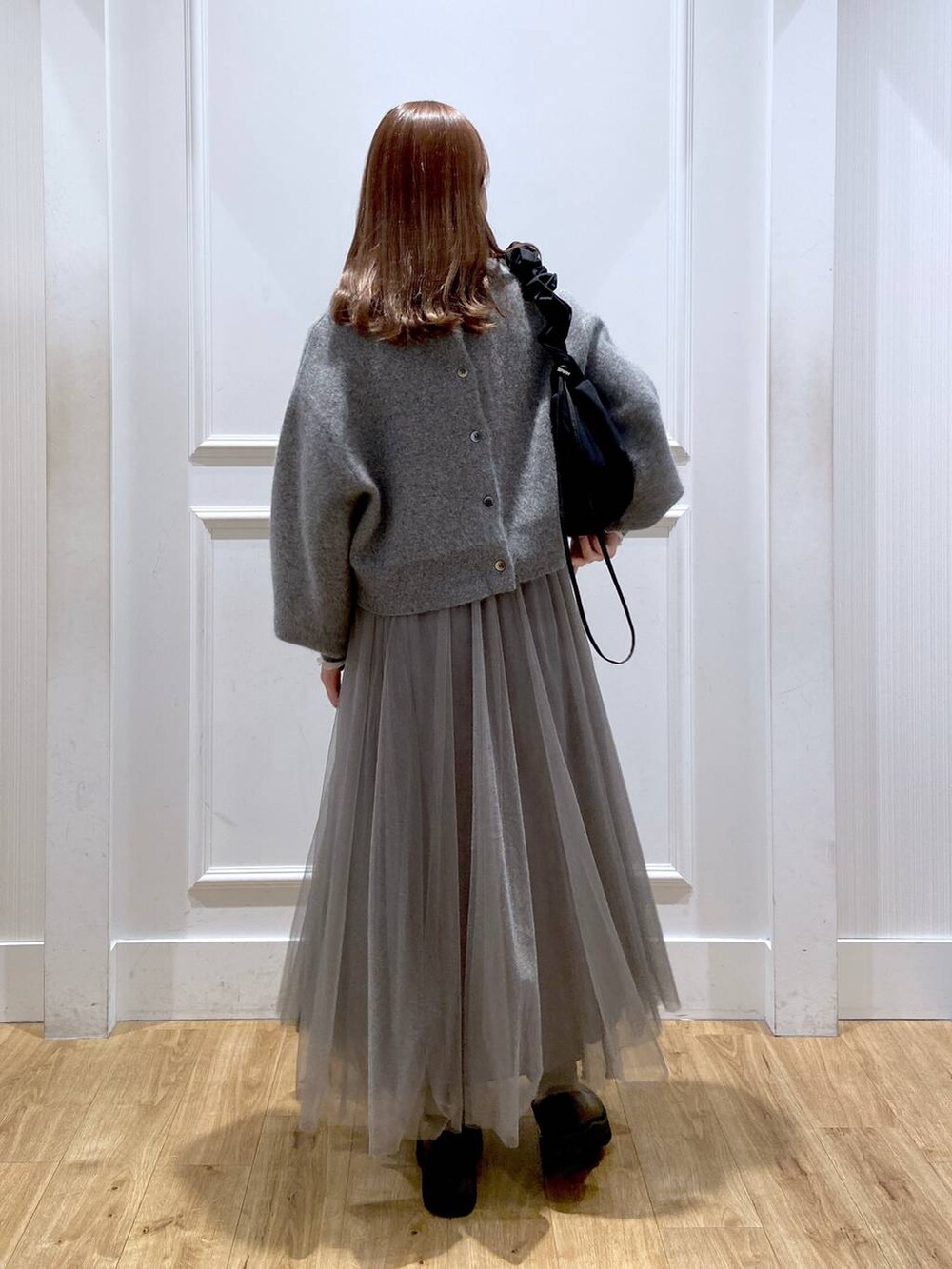 ホワイト系のTシャツ/カットソー、グレー系のカーディガン/ボレロ、ブラック系のブーツを着用したレディースの冬コーディネートの6枚目の写真