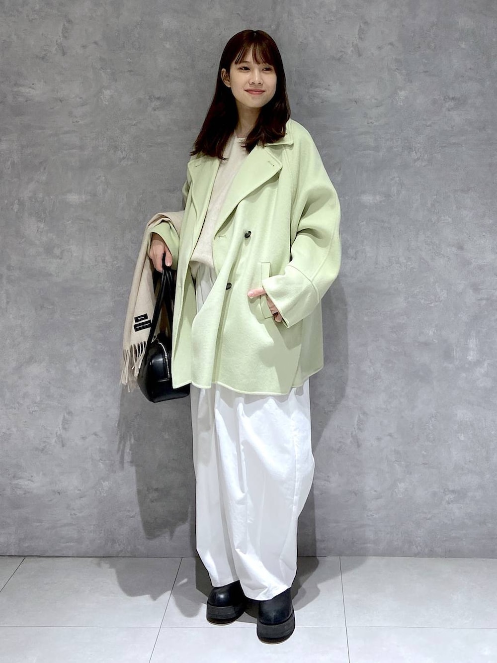 グリーン系のその他アウター、ホワイト系のニット/セーター、ブラック系のブーツを着用したレディースの冬コーディネートの3枚目の写真