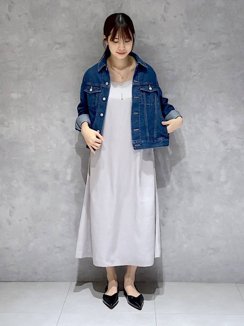 ブルー系のデニムジャケット、グレー系のドレス、ブラック系のパンプスを着用したレディースの秋コーディネートの2枚目の写真