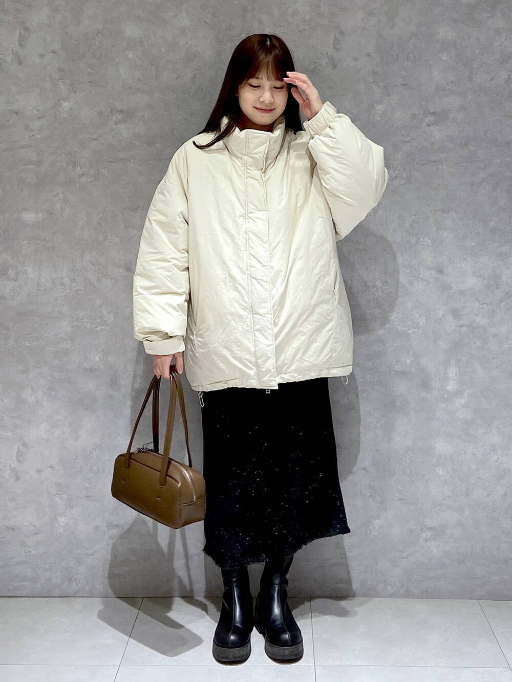ホワイト系のダウンジャケット/コート、グレー系のスカート、ブラック系のブーツを着用したレディースの冬コーディネートの2枚目の写真