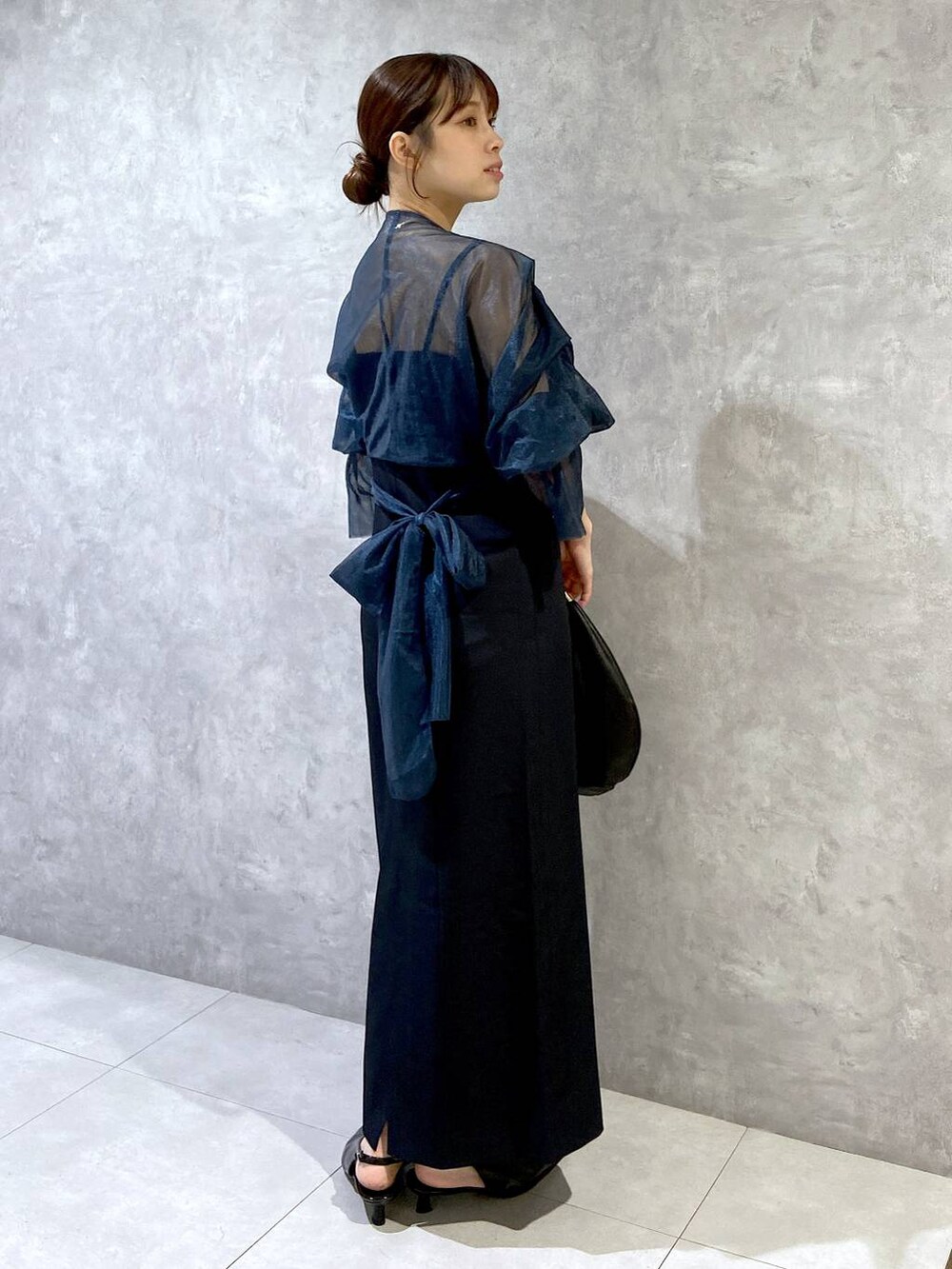 ブラック系のハンドバッグ、ブラック系のパンプス、ブルー系のドレスを着用したレディースの秋コーディネートの2枚目の写真