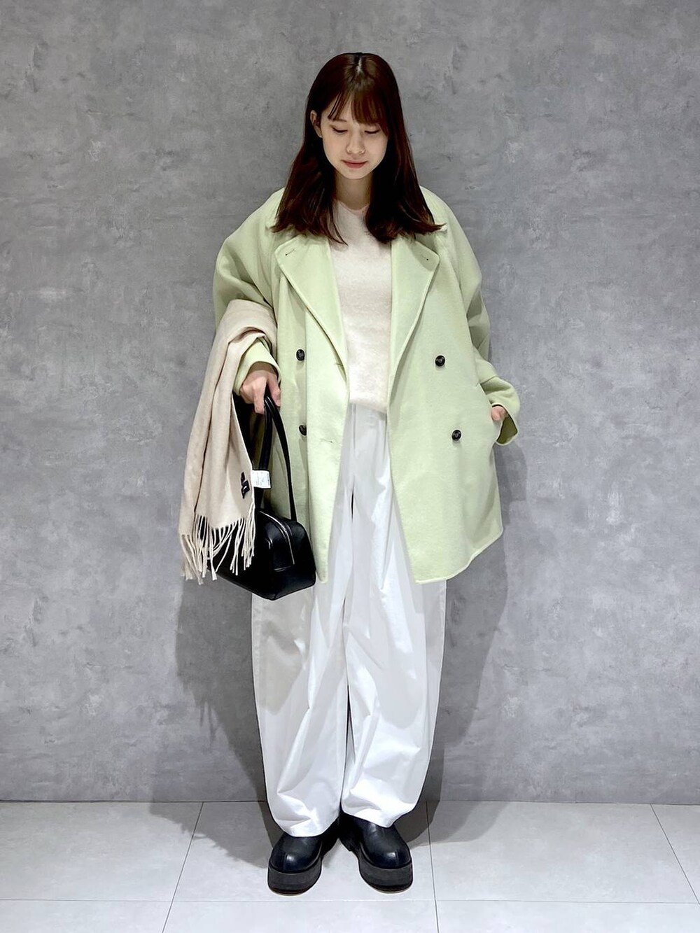 グリーン系のその他アウター、ホワイト系のニット/セーター、ブラック系のブーツを着用したレディースの冬コーディネートの4枚目の写真