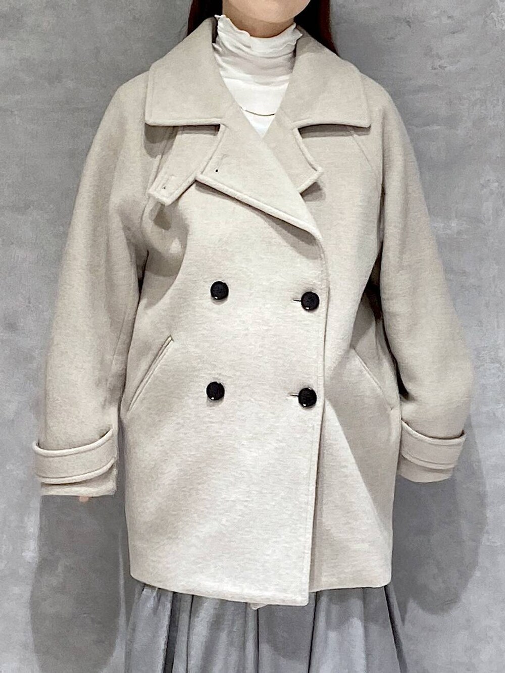 ベージュ系のピーコート、ホワイト系のTシャツ/カットソー、ブラック系のブーツを着用したレディースの冬コーディネートの7枚目の写真