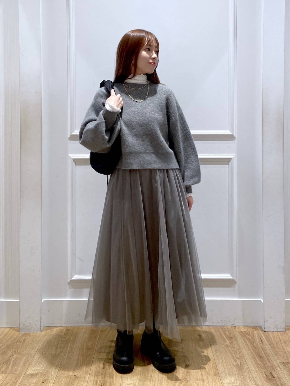 ホワイト系のTシャツ/カットソー、グレー系のカーディガン/ボレロ、ブラック系のブーツを着用したレディースの冬コーディネートの3枚目の写真